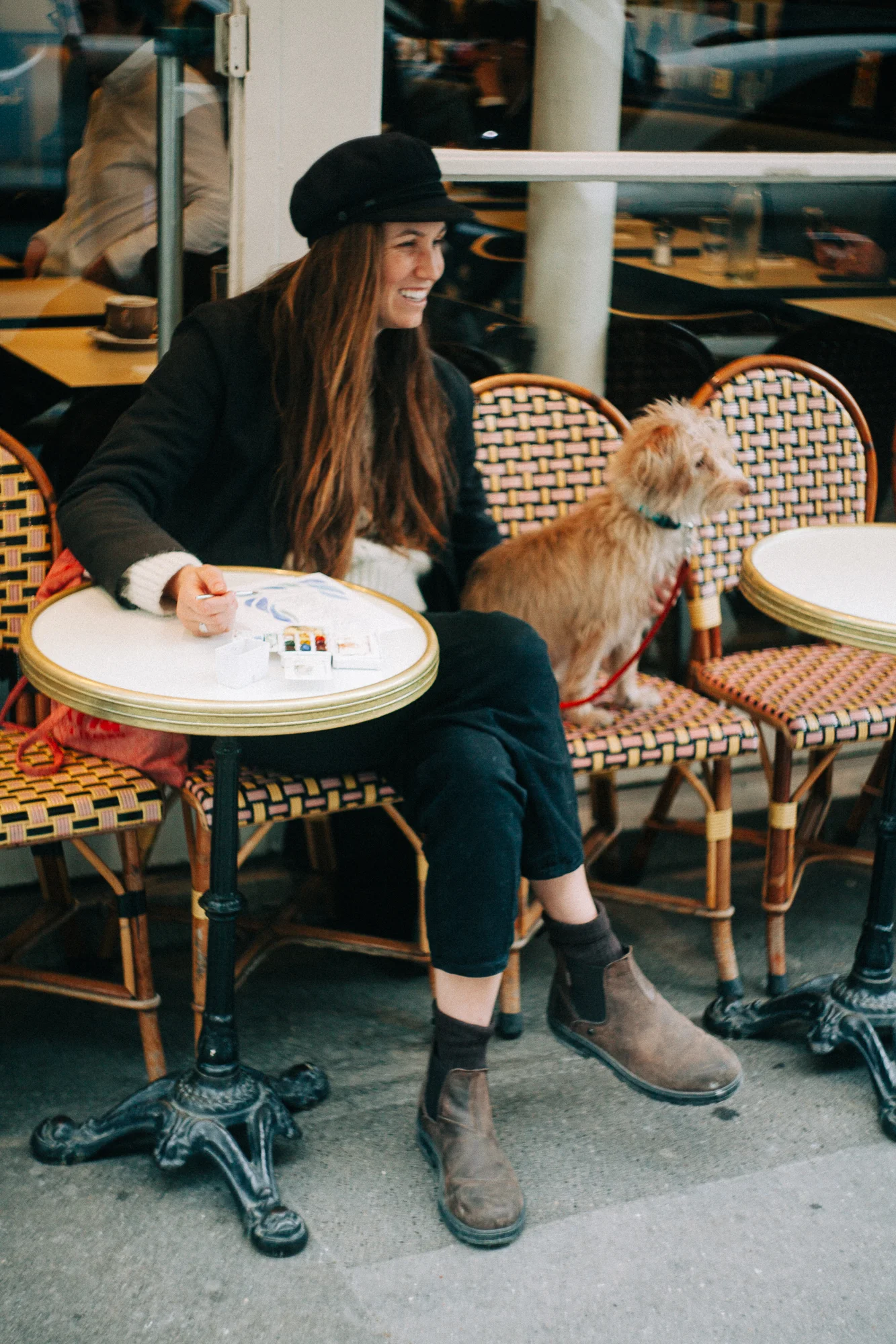 a woman and dog sitting at a bistro    