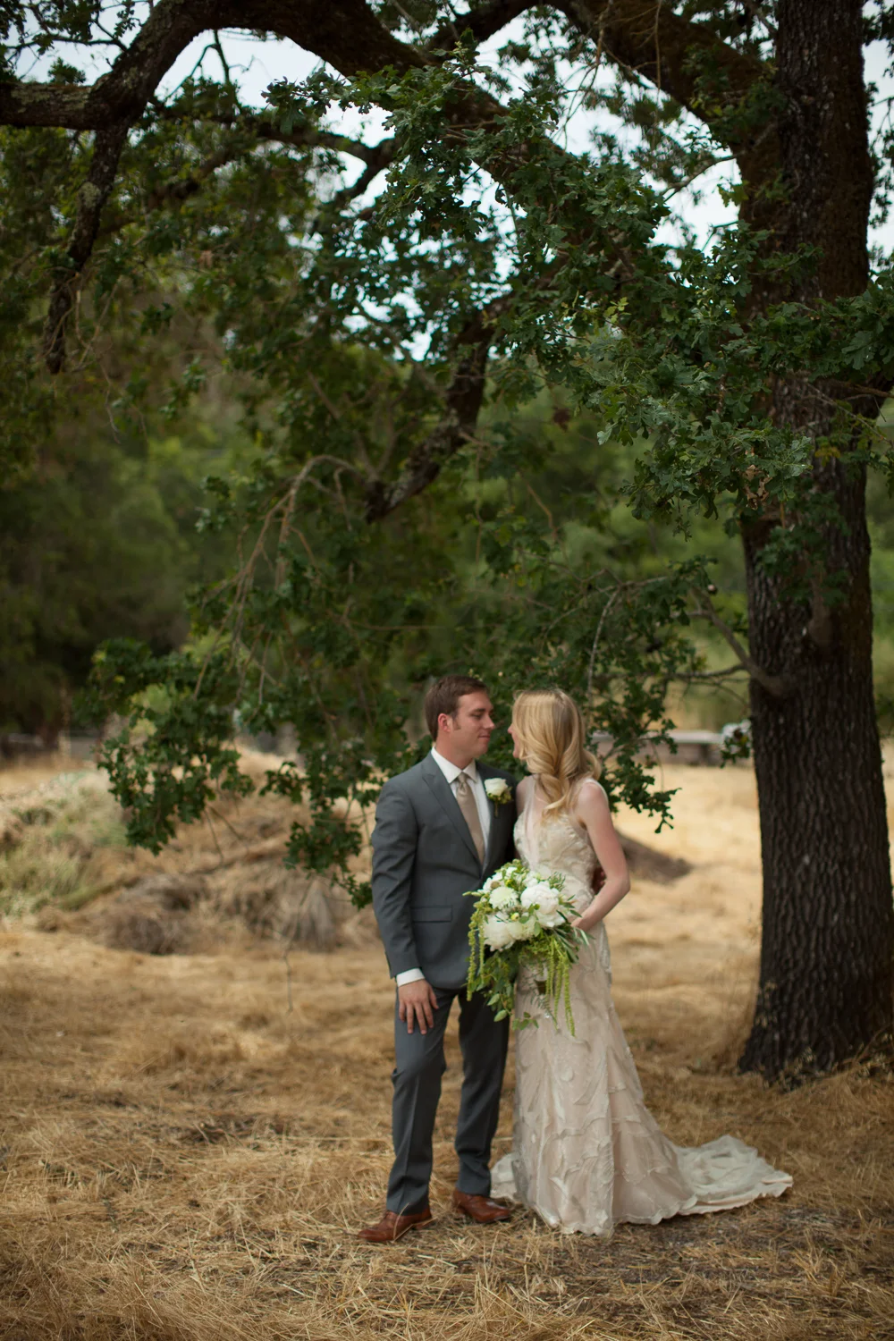 a bride and groom posing under a tree